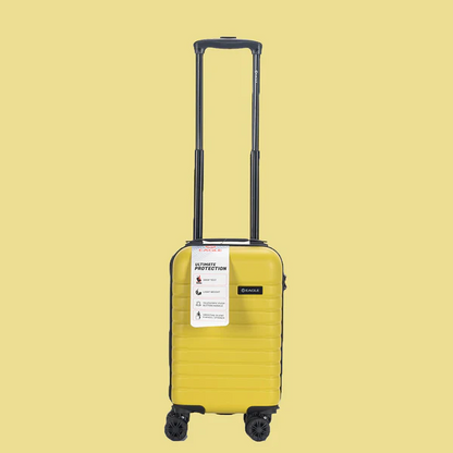 Yellow hard shell carry-on suitcase with four wheels and telescopic handle on beige background2